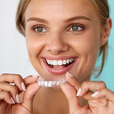Patient smiling while holding teeth whitening tray