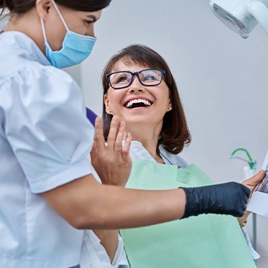Woman smiling with dentist while reviewing X-ray
