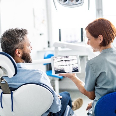 Smiling dental assistant and patient looking at X-ray