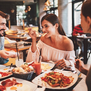 Group of friends smiling while eating at restaurant