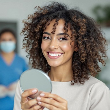 Woman smiling while holding small mirror