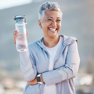 Woman smiling with water bottle on hike outside