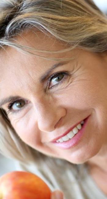 Smiling older woman holding an apple