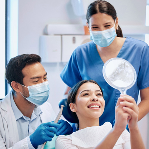 Patient looking at reflection in mirror with dentist
