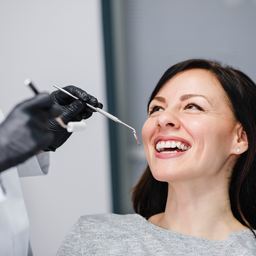 Woman sitting in dental chair smiling up at dentist