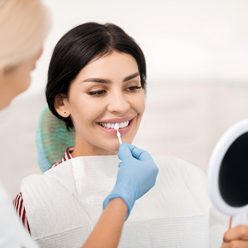 Female patient checking mirror while having teeth shade matched
