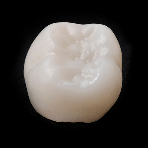 Close up of dental crown on black surface