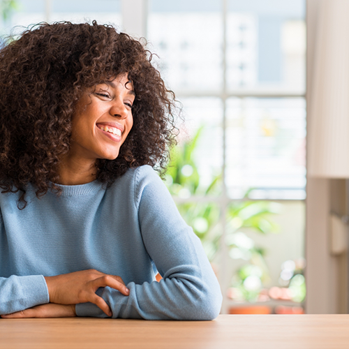 Woman in blue shirt sitting at table and smiling