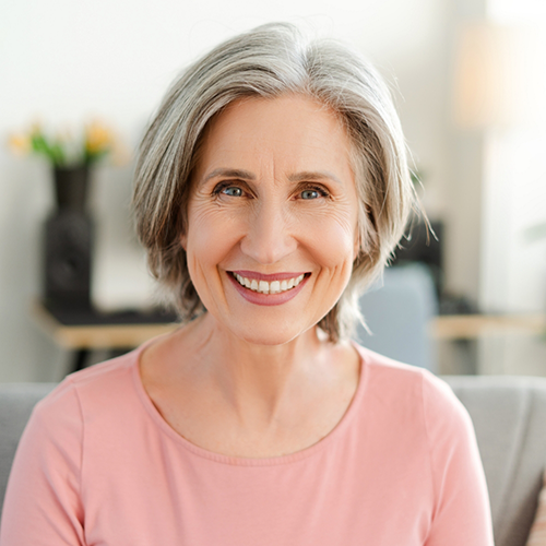 Woman in pink shirt smiling at home