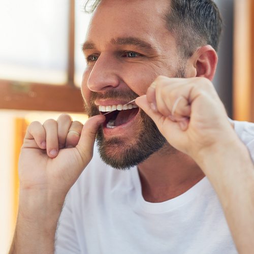 Bearded man flossing his upper teeth