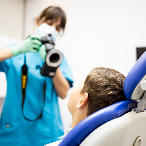 Little boy sitting in chair while dentist prepares to take X rays