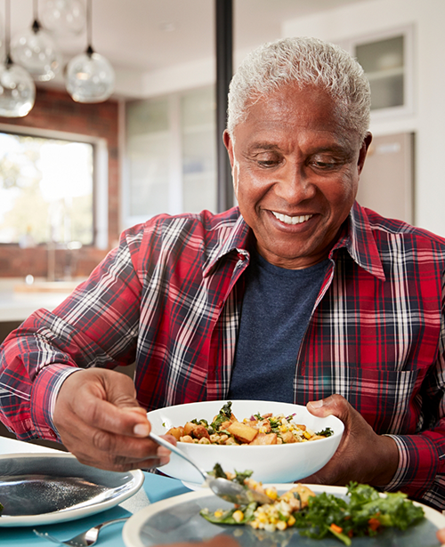 Smiling man scooping vegetables into bowl