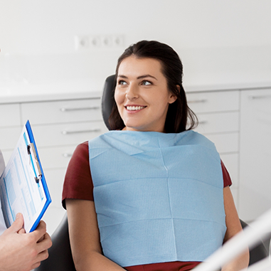 Woman smiling at dentist holding clipboard