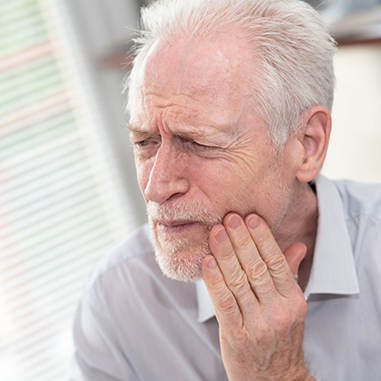 Senior man rubbing jaw in pain