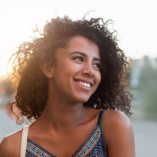 Woman with curly hair smiling outside