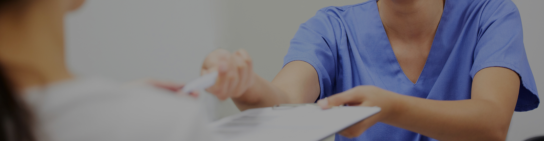 Female dental team member handing pen to patient