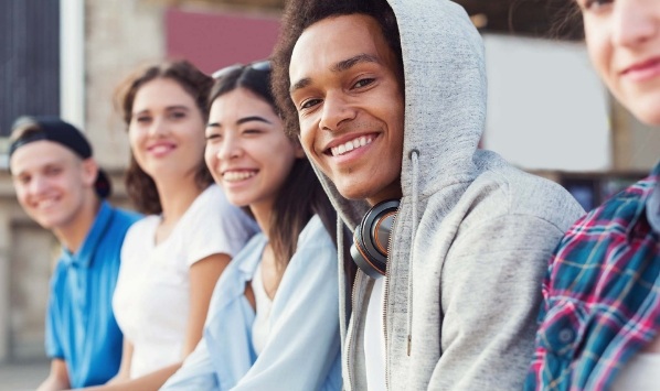 Group of smiling young adults sitting on bench
