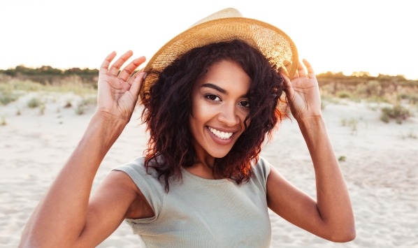 Smiling young woman on beach in sunhat