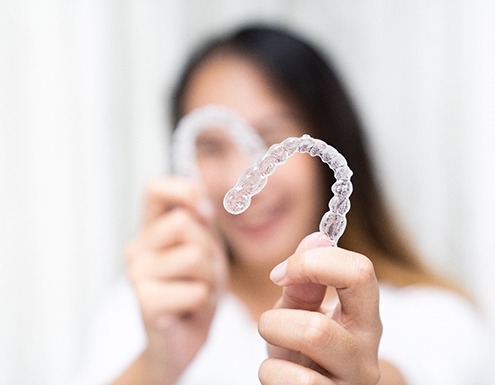 Smiling woman holding clear aligners