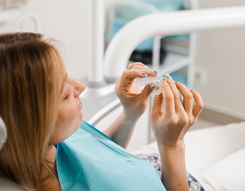 Patient holding clear aligner in treatment chair