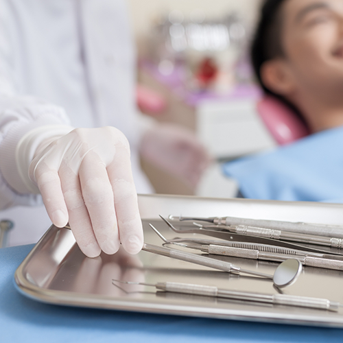 Dentist reaching to pick up dental instrument
