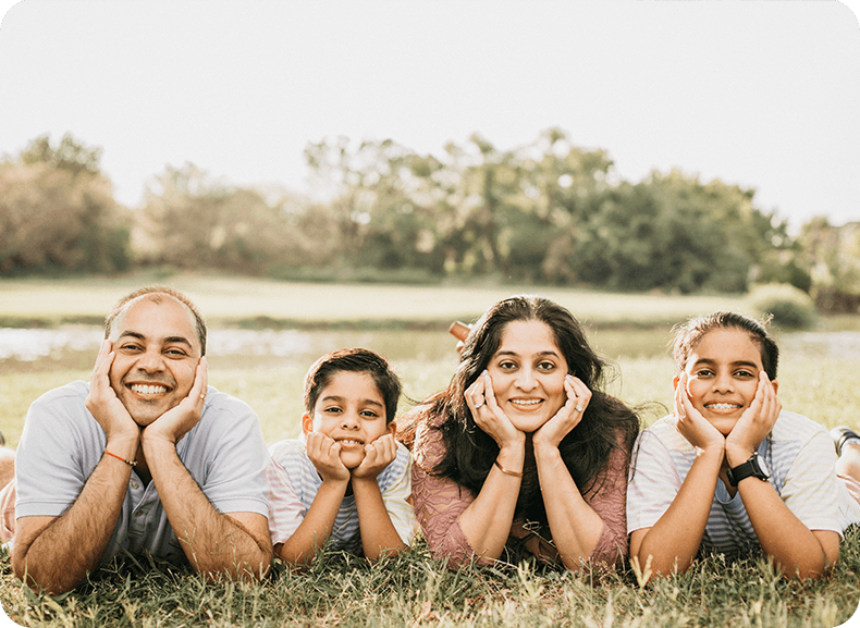 Dr. Mansi Talsania and her family lying down outside and smiling