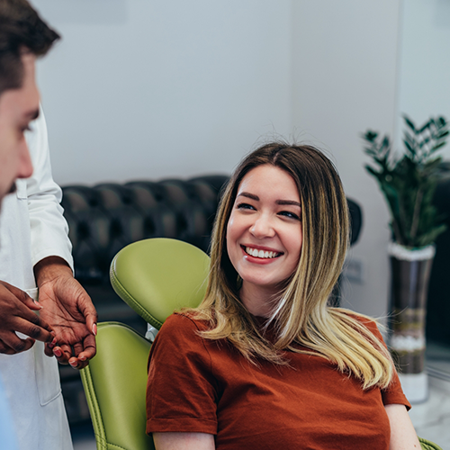 Blonde woman in dental chair smiling at dentist