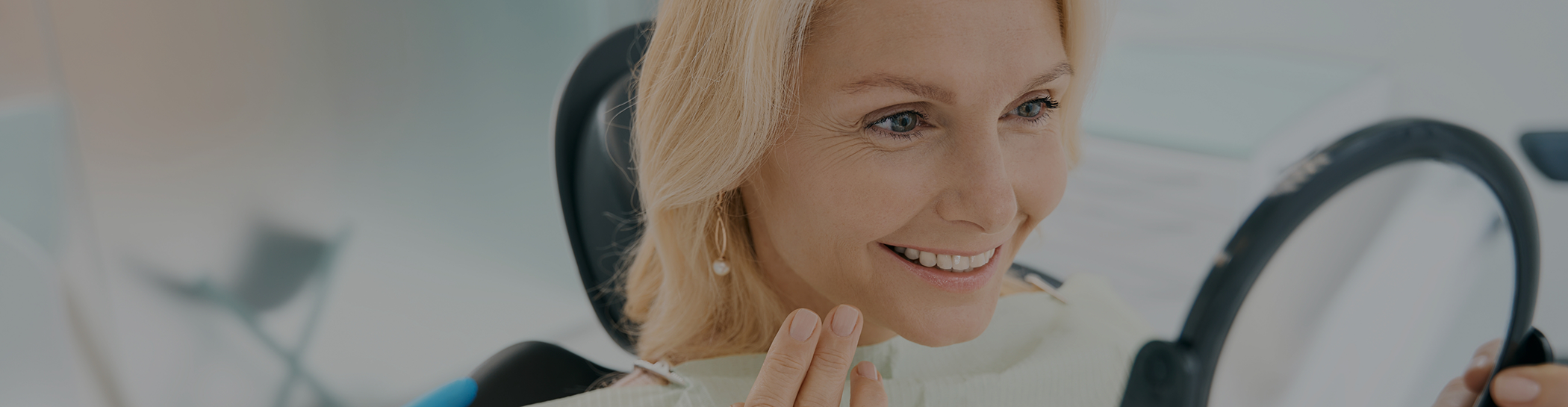 Female patient checking smile in handheld mirror
