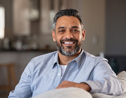 Bearded man sitting on couch and smiling