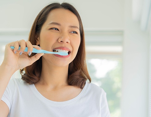 Woman in white shirt brushing her teeth