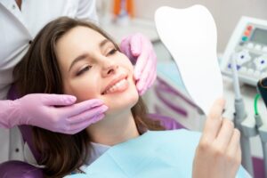 Patient smiling into mirror in dentist's chair. 