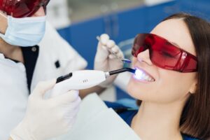 Dentist whitening patient’s teeth.